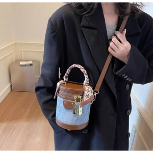 Detail of blue denim bucket bag with leather base and silk scarf wrapped handle