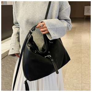 Detail of black large capacity tote bag featuring matte leather stitching and silver rings