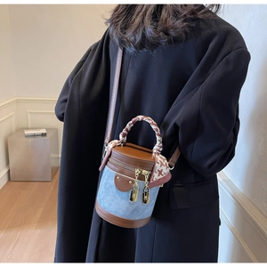 Detail of blue denim bucket bag with brown leather trim and silk scarf on the handle