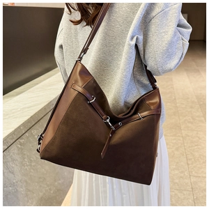 Detail of a large brown hobo bag with matte leather texture and silver hardware