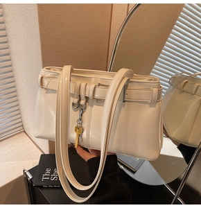Detail view of cream shoulder bag featuring faux leather texture and key charm detail