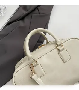 Close-up of cream leather Boston bag with litchi texture and gold hardware details