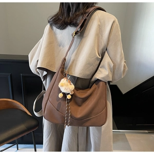 Brown leather hobo dumpling bag with adjustable strap and cute beige plush pendant detail