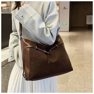 Detail of dark brown leather tote bag with vintage matte texture and stylish buckle strap