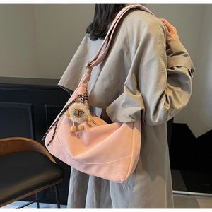 Pink crescent crossbody bag detail with plush lion charm and adjustable suede strap