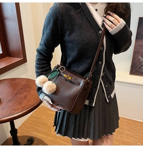 Deep brown small square bag with golden turn-lock and soft pompom charm detail
