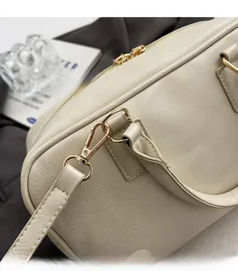 Detailed close-up of premium golden hardware and lychee pattern leather on a cream handbag