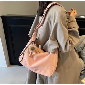 Detail of pink faux suede hobo bag with wide shoulder strap and cute lion pendant