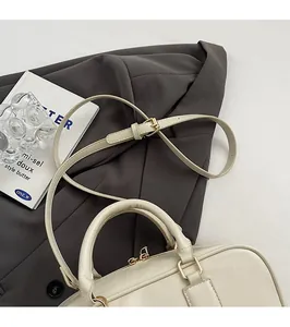 Detail of adjustable shoulder strap and gold hardware on cream Boston handbag