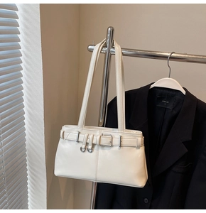 Close-up of cream leather shoulder bag with silver ring buckles on a metal rack