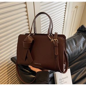 Detail der dunkelbraunen Leder-Shopper-Tasche mit Knotendekor und Goldbeschlägen