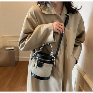 Detail of canvas bucket bag with black leather trim and silk scarf handle on a model