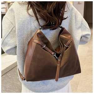 Detail view of large brown faux leather tote backpack on model in urban minimalist style
