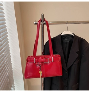 Detail of red patent leather shoulder bag with adjustable buckles and gold key charm