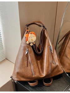 Retro brown oversized shoulder bag with silver zippers and orange plush monster charm