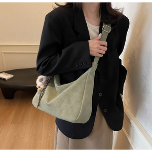 Detail view of grass green crescent crossbody bag with plush charm and adjustable strap