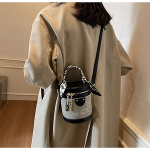 Fashion bucket bag with silk scarf handle worn over a beige coat for a stylish street look