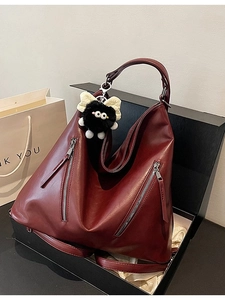 Vintage burgundy leather tote bag with silver zippers and plush monster charm in a gift box