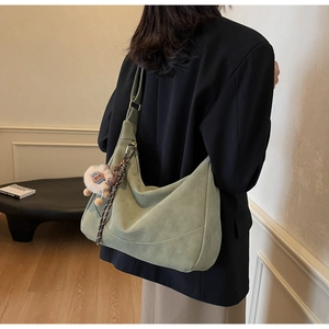Detail of green suede hobo bag featuring a cute lion plush charm on the shoulder strap
