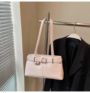 Macro detail of a soft pink leather motorcycle bag with silver buckles and a shoulder strap
