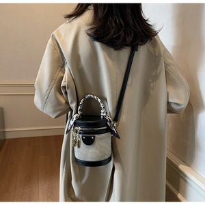 Detail of color-block bucket bag with gold padlock charm and patterned silk scarf handle