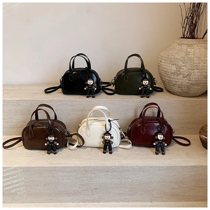 Mini-Boston-Taschen in fünf Farben mit Affenanhänger auf einem abgestuften Display-Ständer