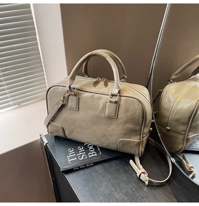 Detail view of khaki leather Boston bag featuring gold hardware and a reinforced corner design