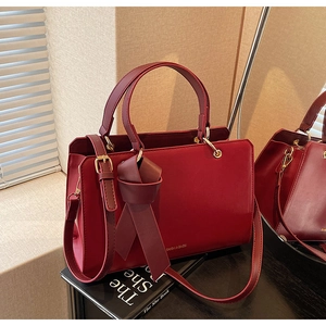 Detailansicht der dunkelroten Ledertasche mit eleganter Schleife und Metallakzenten