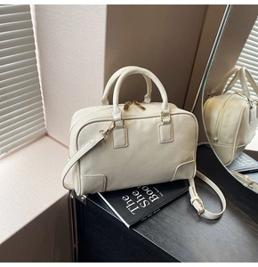 Detail of a creamy beige Boston bag showing golden hardware and fine leather texture