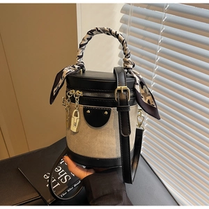 Detail of a color-block bucket bag with woven texture and scarf-wrapped top handle