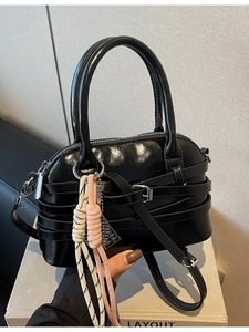 Glossy black shell-style shoulder bag with decorative straps and woven charms