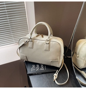 Detail of cream Boston handbag featuring fine leather texture and golden metal hardware