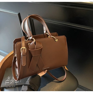 Detail der dunkelbraunen Ledertasche mit Knotendesign und goldenen Beschlägen