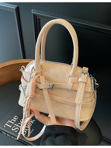 Fashionable shell pink crossbody bag with metal buckles and decorative woven strap detail