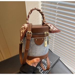 Detail of denim bucket bag with leather trim and houndstooth scarf wrapped handle