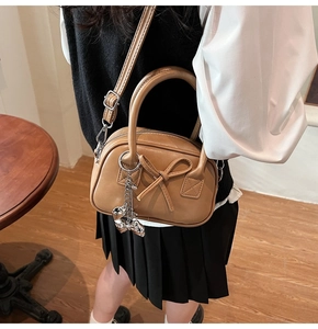 Borsa bowling retrò marrone con fiocco e ciondolo a orsetto indossata da una modella