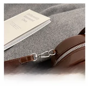 Nahaufnahme der silbernen Metallhaken und Nähte an der braunen Leder-Handtasche