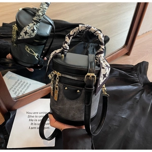 Detail of a denim and black leather bucket bag with houndstooth silk scarf on the handle