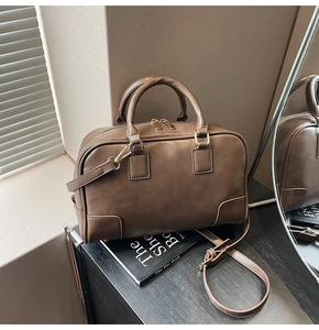 Close-up of brown textured leather Boston bag with gold dual zippers and shoulder strap
