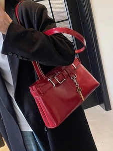 Vintage dark red glossy leather handbag with gold key charm shown on a model
