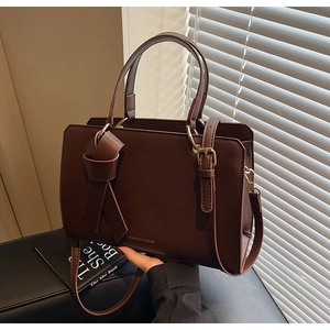 Detailansicht der dunkelbraunen Ledertasche mit Goldbeschlägen und Knoten-Design