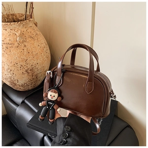 Detail der vintage braunen Zylindertasche mit Cartoon-Puppenanhänger und Leder-Textur