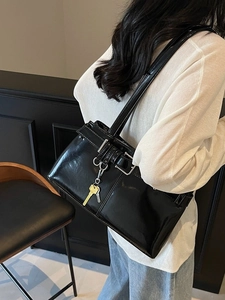 Retro black glossy motorcycle tote bag with silver buckles and a gold key charm