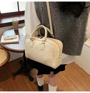 Macro detail of creamy white Boston bag with L-shaped leather corner patches and stitching