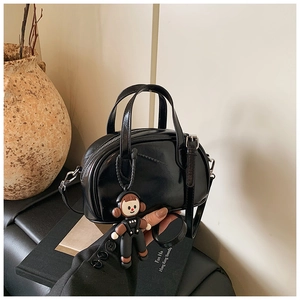 Detail einer kleinen schwarzen Lackleder-Handtasche mit Hochglanz-Finish und Anhänger
