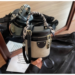 Macro shot of two-tone bucket bag with leather trim and houndstooth silk scarf detail