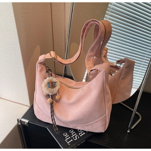 Detail of pink faux suede hobo bag with lion plush charm and golden metal hardware