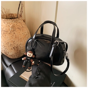 Detail der schwarzen glänzenden Leder-Pillow-Bag mit Silberbeschlägen und Puppenanhänger