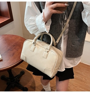 Close-up of cream Boston handbag featuring leather reinforcement corners and dual handles