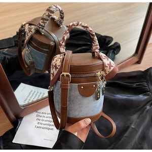 Detail of bucket bag featuring brown leather, blue denim patchwork, and silk scarf handle